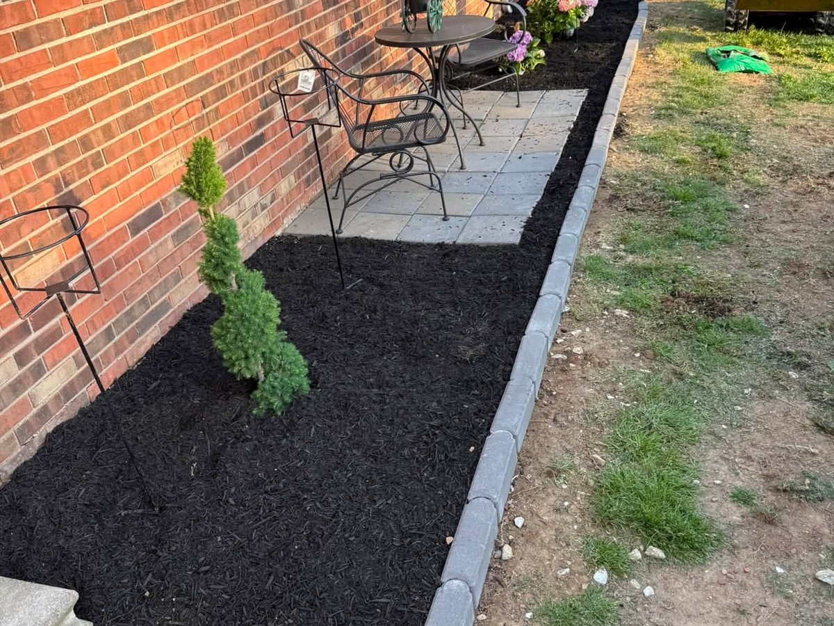 Paver patio with a bordered mulch bed and new plantings